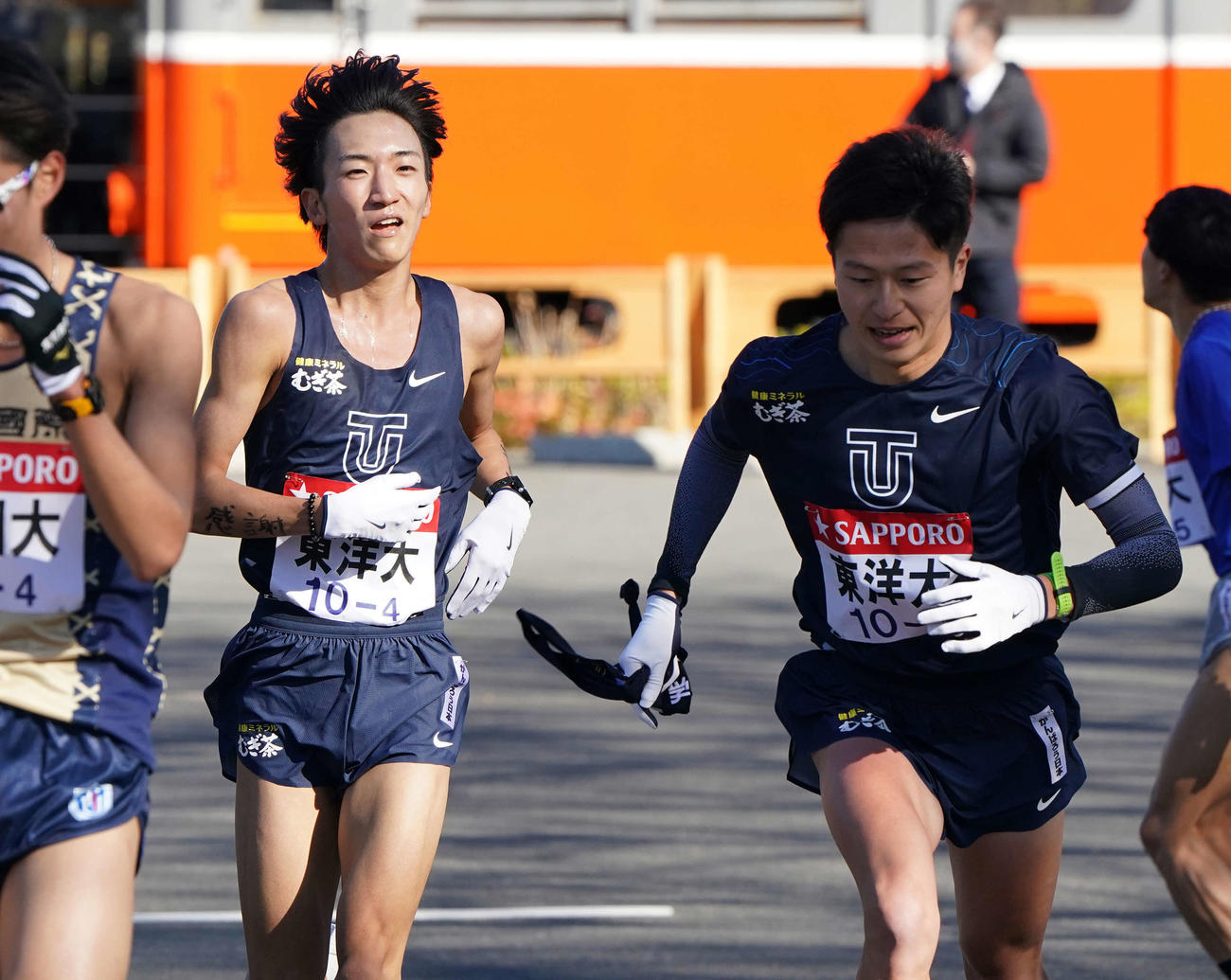 小田原中継所で5区宮下（右）にたすきを渡す東洋大4区吉川（撮影・鈴木みどり）