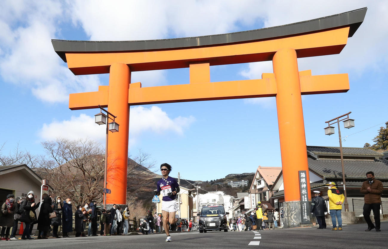 箱根神社の大鳥居を走り抜ける明大5区鈴木（撮影・狩俣裕三）