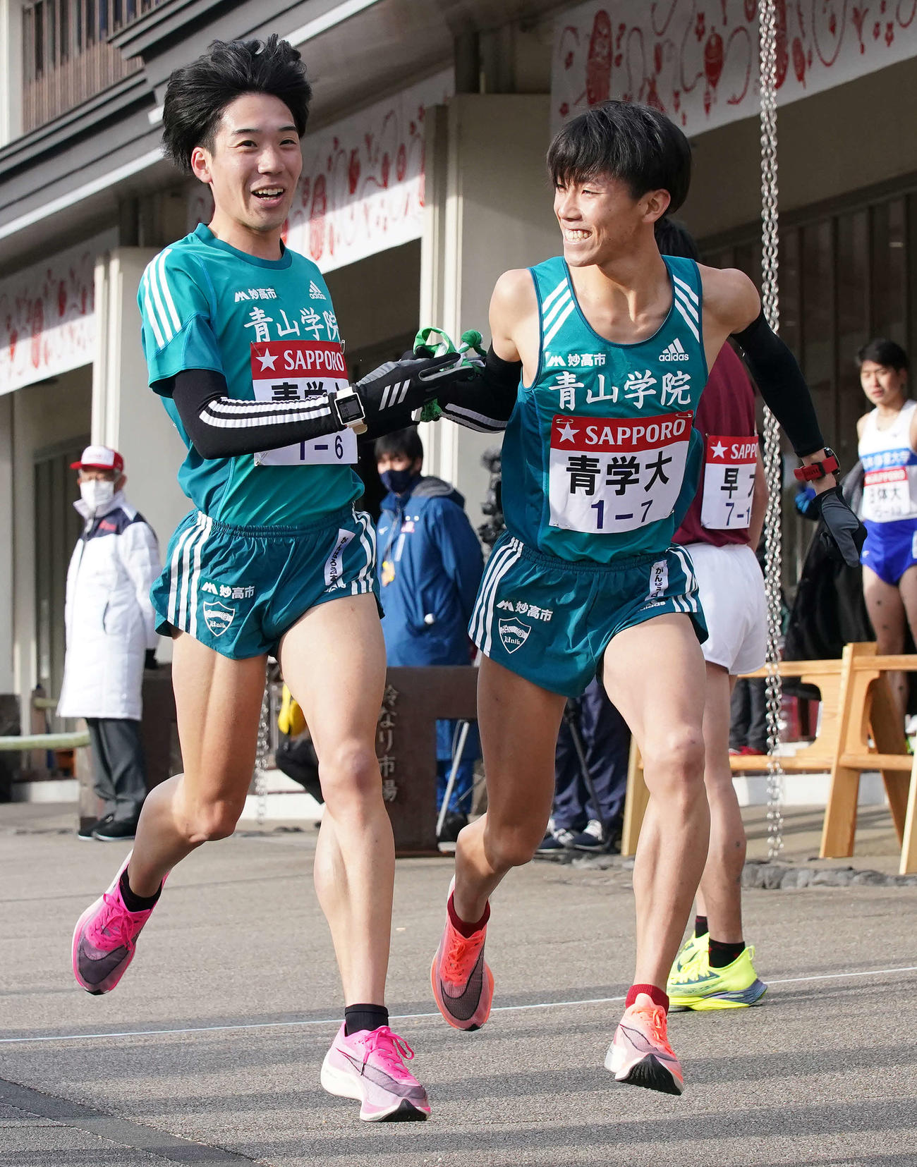 小田原中継所で7区近藤（右）にたすきを渡す青学大6区高橋（撮影・鈴木みどり）