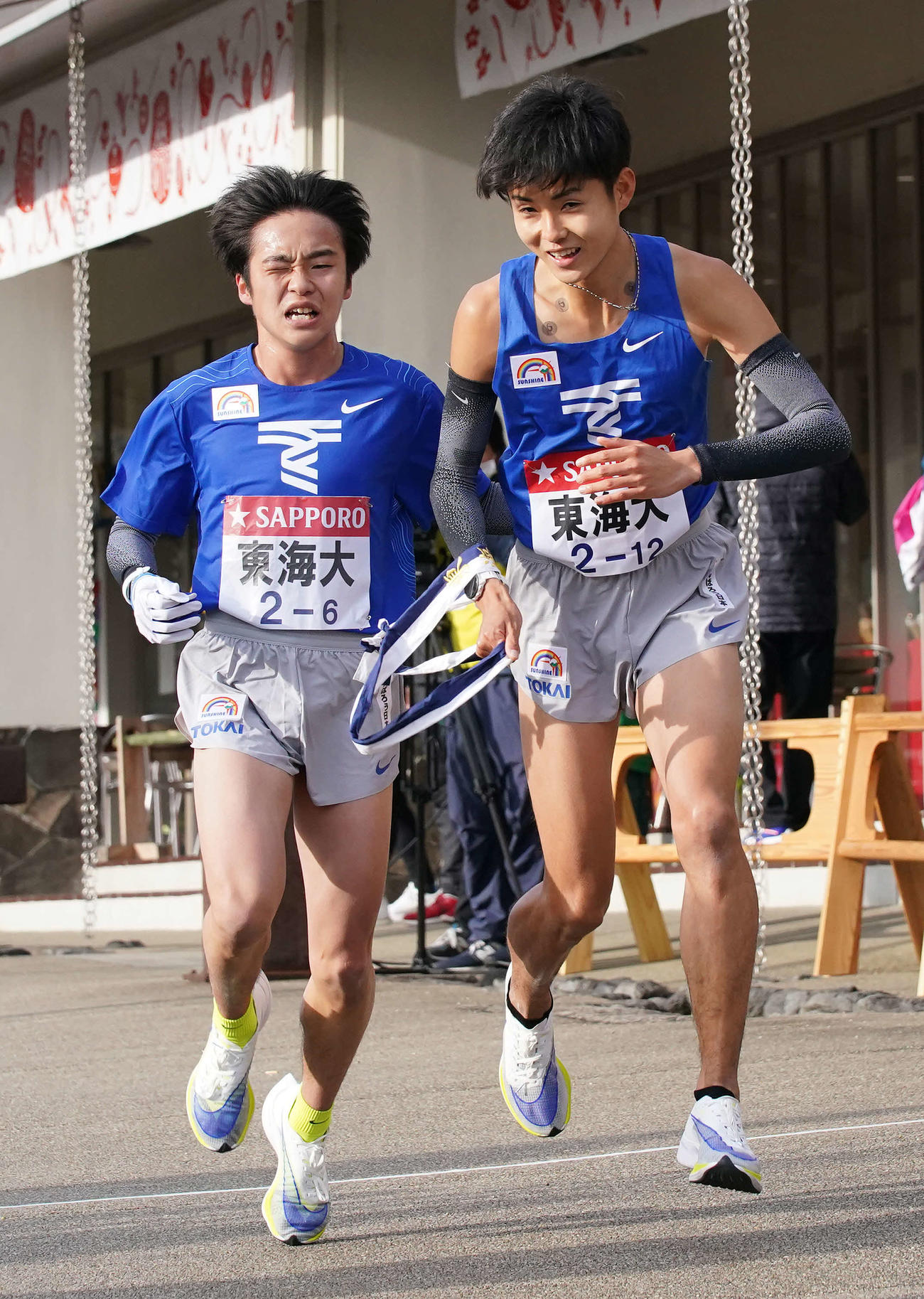 小田原中継所で7区本間（右）にたすきを渡す東海大6区川上（撮影・鈴木みどり）