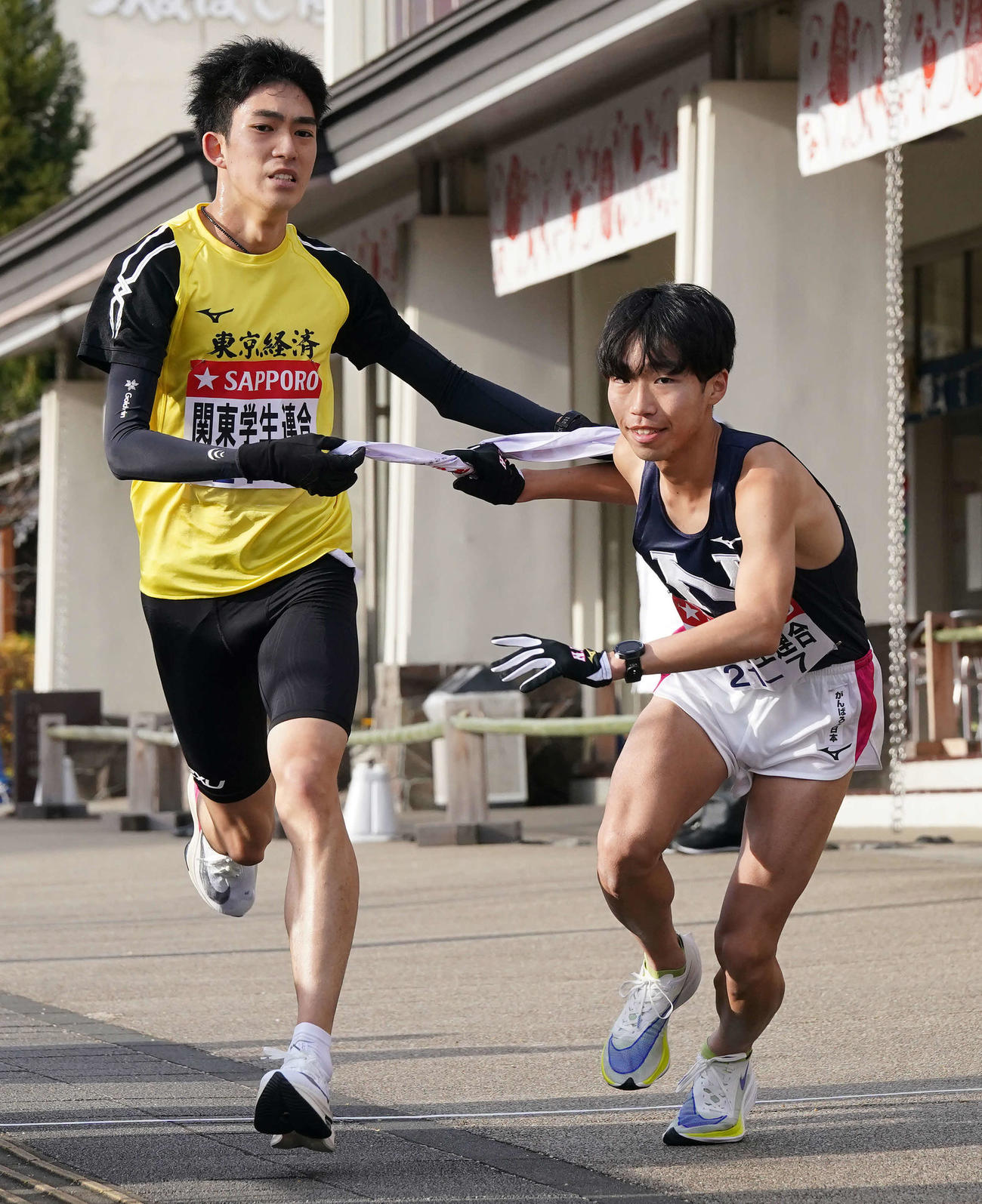 小田原中継所で7区の日大・小坂（右）にたすきを渡す関東学生連合6区の東経大・大川（撮影・鈴木みどり）