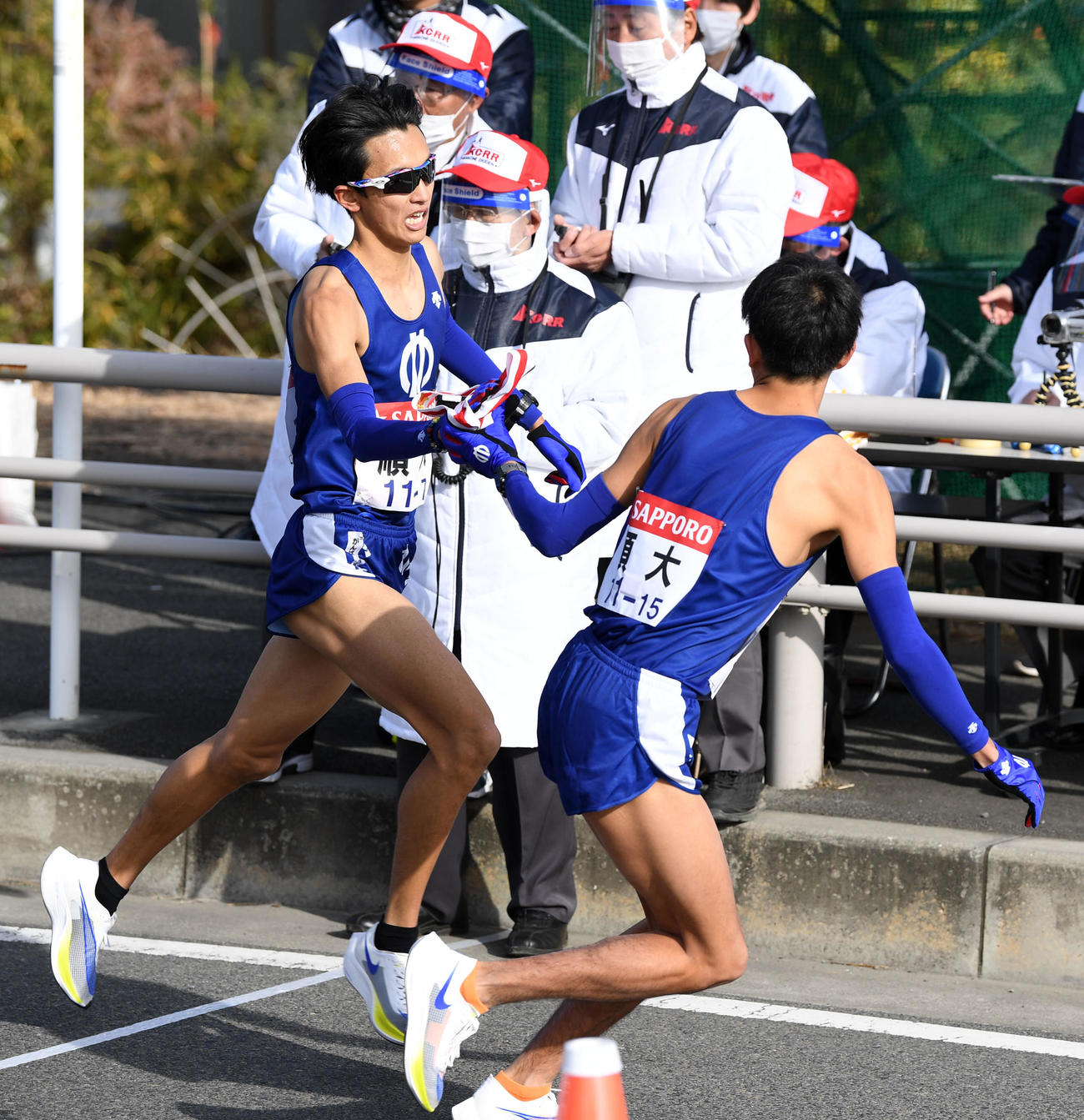 平塚中継所、タスキをつなぐ順大7区小島（左）と8区西沢（撮影・横山健太）