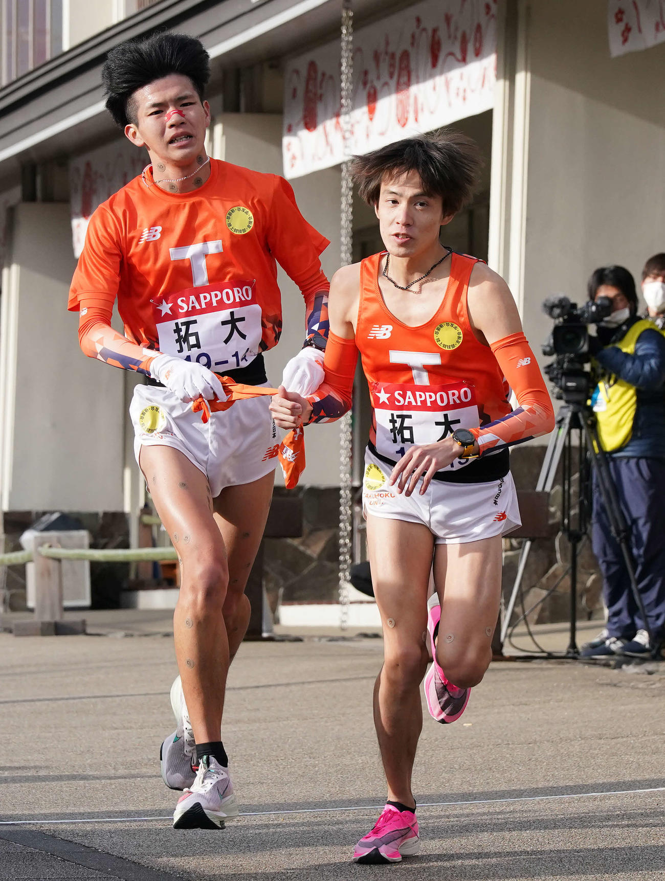 小田原中継所で7区吉村（右）にたすきを渡す拓大6区佐々木（撮影・鈴木みどり）