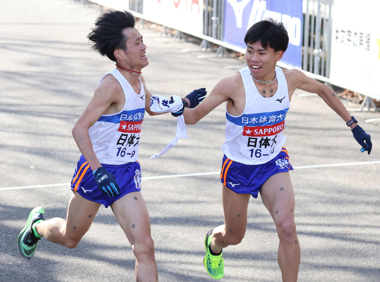 鶴見中継所、日体大10区名村樹哉（右）にタスキをつなぐ9区野上（撮影・河野匠）