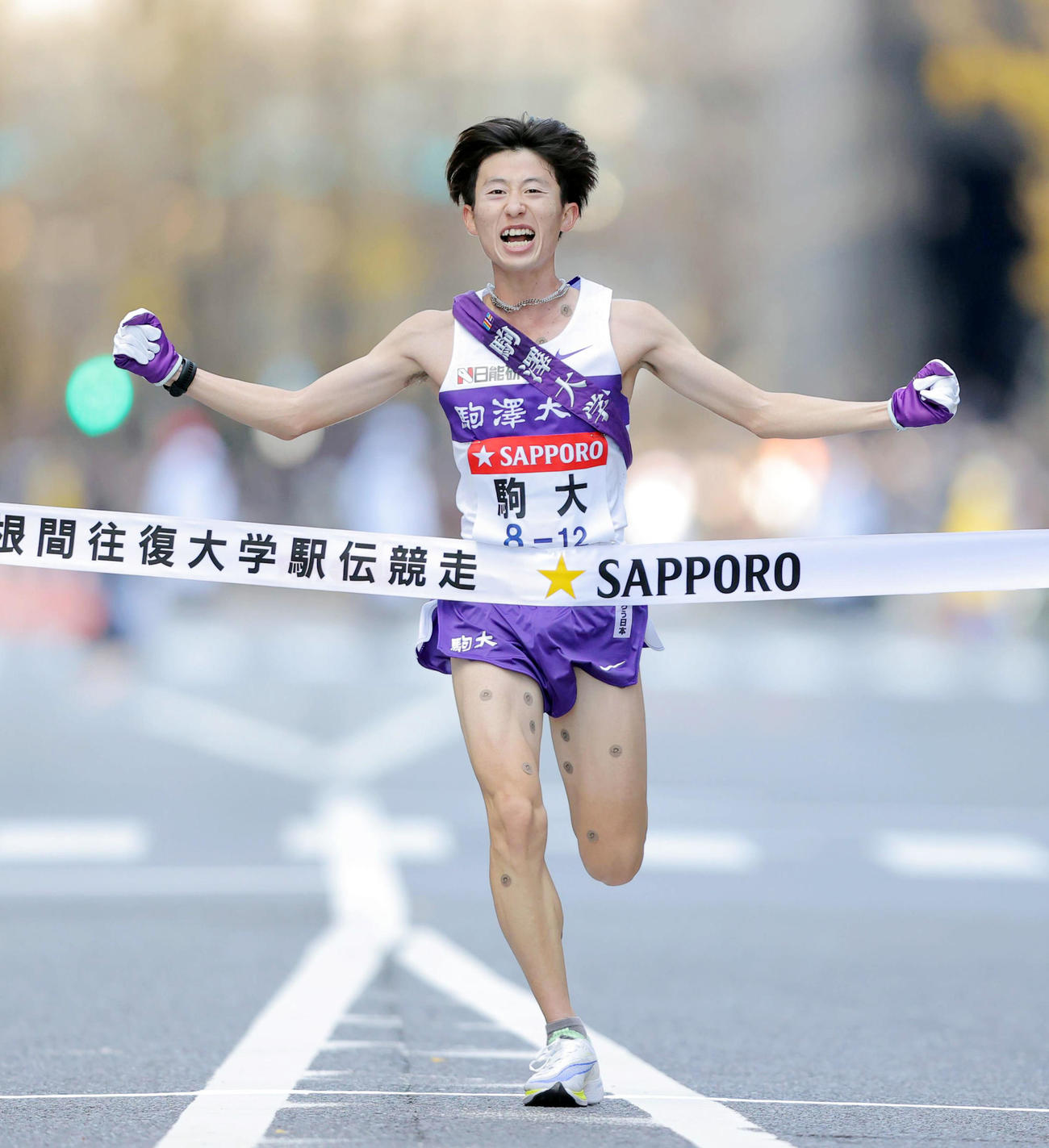 総合優勝のゴールテープを切る駒大10区石川（代表撮影）