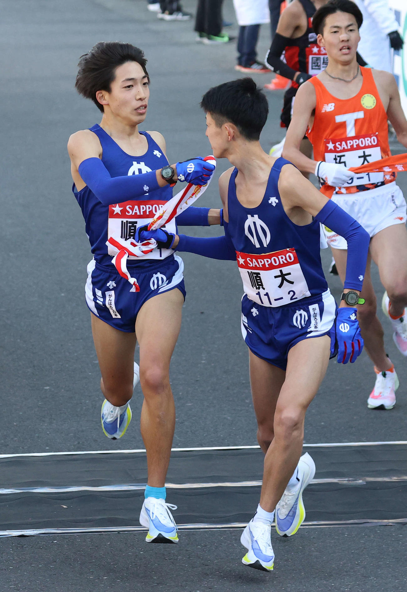 11番目、10位でタスキをつなぐ順大1区三浦龍司（左）と2区野村（撮影・河野匠）