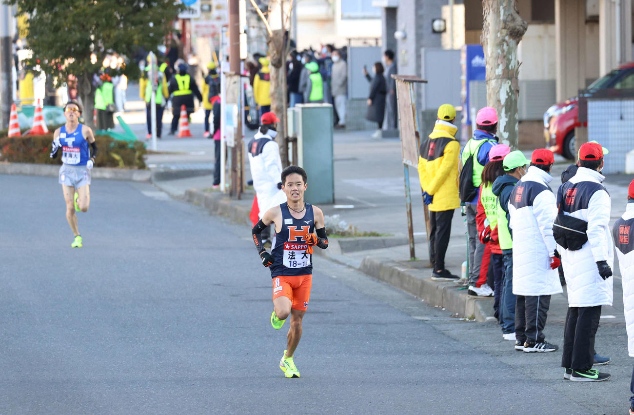 沿道に観客のいない中、トップで鶴見中継所に入る法大1区鎌田（手前）。後方は東海大1区塩沢（撮影・河野匠）