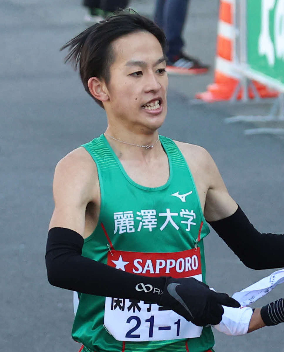 第97回東京箱根間大学駅伝競走　往路　関東学連選抜1区麗沢大・難波天（左）からタスキを受けて駆け出す2区亜大・河村悠＝2021年1月2日