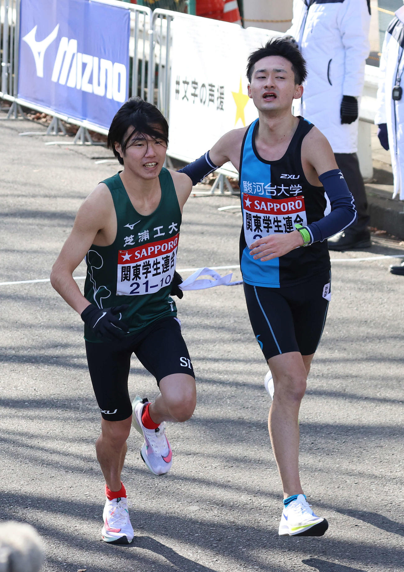 鶴見中継所、関東学生連合9区駿河台大・町田（右）からタスキを受けて駆け出す10区芝浦工大・松川雅虎（撮影・河野匠）