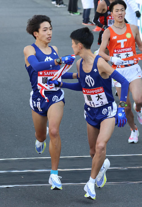 11番目、10位でタスキをつなぐ順大1区三浦龍司(左)と2区野村(撮影・河野匠)