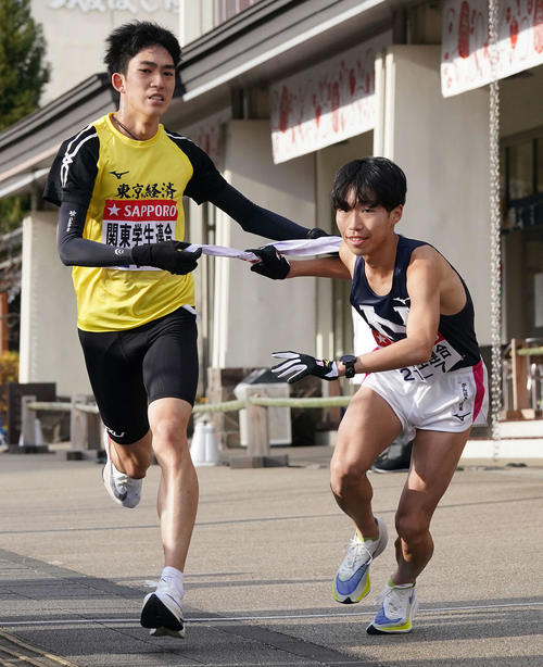 小田原中継所で7区の日大・小坂(右)にたすきを渡す関東学生連合6区の東経大・大川(撮影・鈴木みどり)
