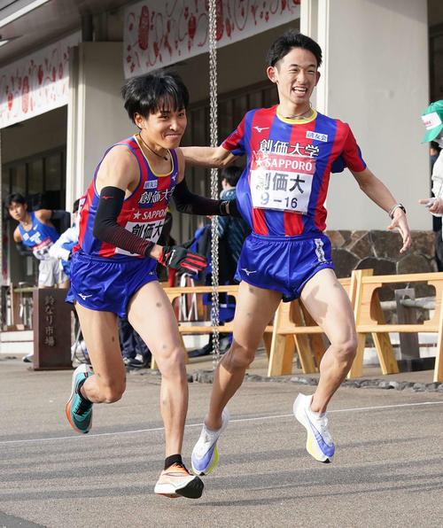 小田原中継所で7区原富(左)にトップでたすきを渡す創価大6区浜野(撮影・鈴木みどり)