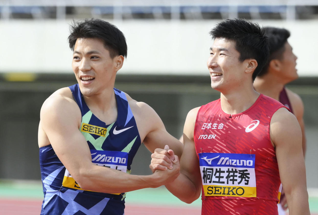 男子100メートル決勝を終え、健闘をたたえ合う優勝した山県（左）と3位の桐生（共同）
