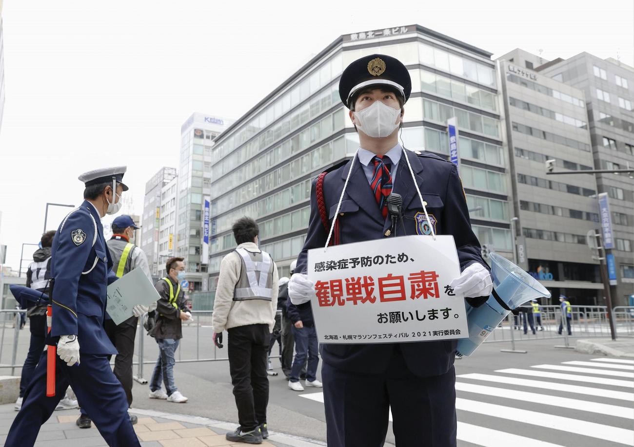 札幌市で開催される東京五輪マラソンのテスト大会で、観戦自粛を呼び掛ける案内を掲げる警備員（共同）