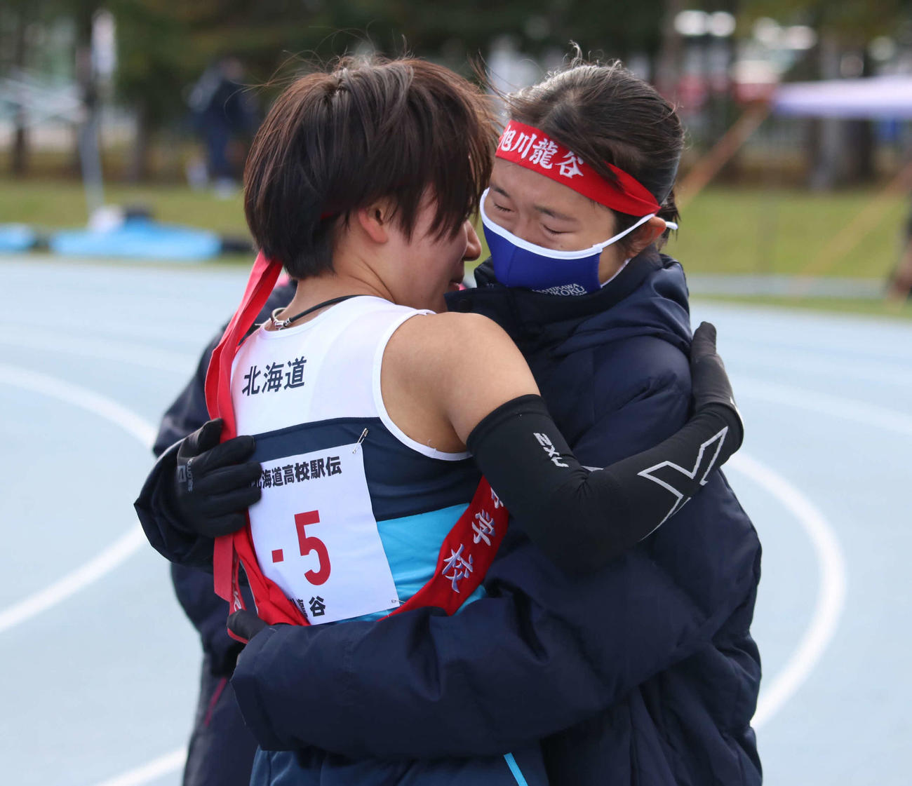優勝を決め抱き合う旭川龍谷のアンカー足沢（左）と1区を走った石川（撮影・山崎純一）