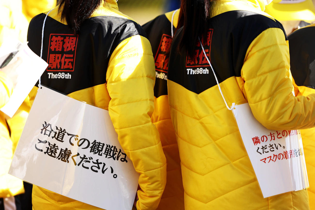 沿道観戦を控えるように促すカードを肩にかけるボランティア（撮影・河田真司）