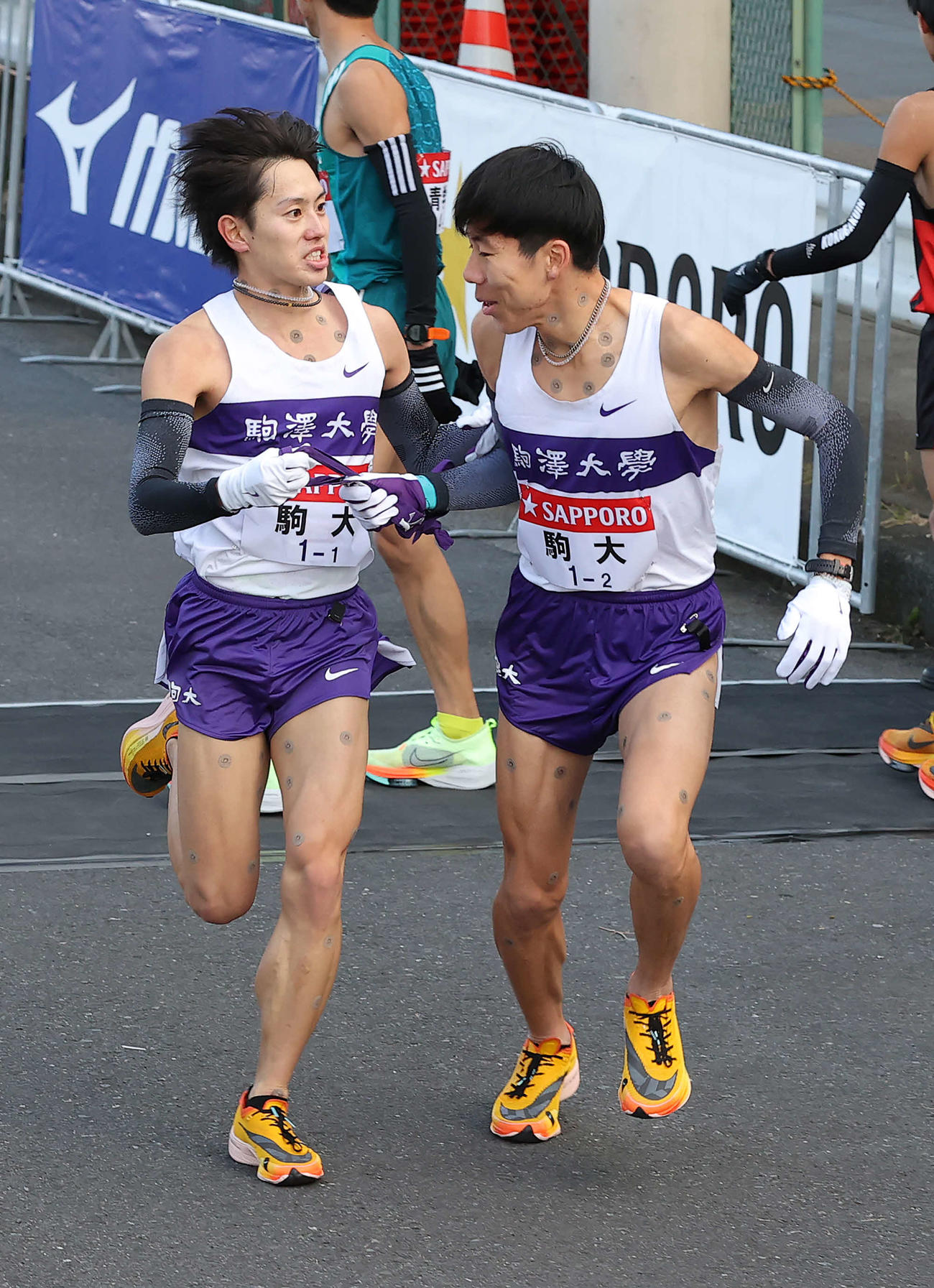鶴見中継所、2位でたすきをつなぐ駒大1区唐沢（左）と2区田沢（撮影・河野匠）