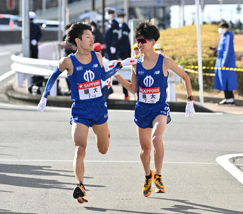 戸塚中継所で順大8区津田（左）は9区野村にたすきを渡す（撮影・滝沢徹郎）