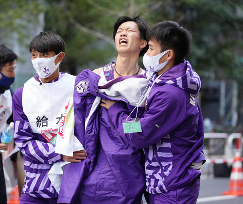 3位でゴールし、チームメイトに抱えられる駒大10区青柿（撮影・菅敏）