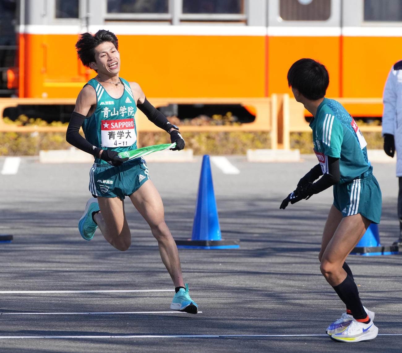 青学大4区飯田貴之（左）は小田原中継所トップで5区若林宏樹にたすきを渡す（撮影・鈴木みどり）