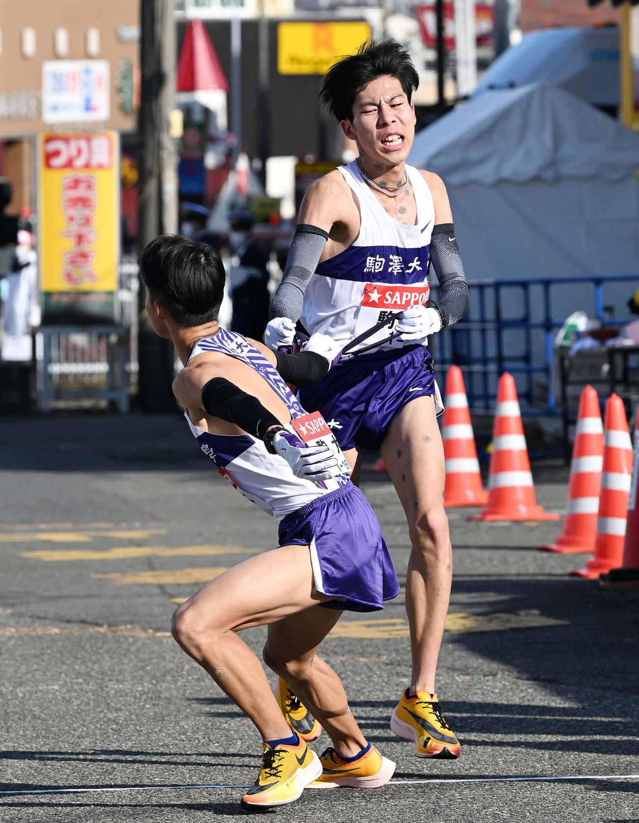 戸塚中継所で駒大2区田沢（右）は3区安原にたすきを渡す（撮影・滝沢徹郎）