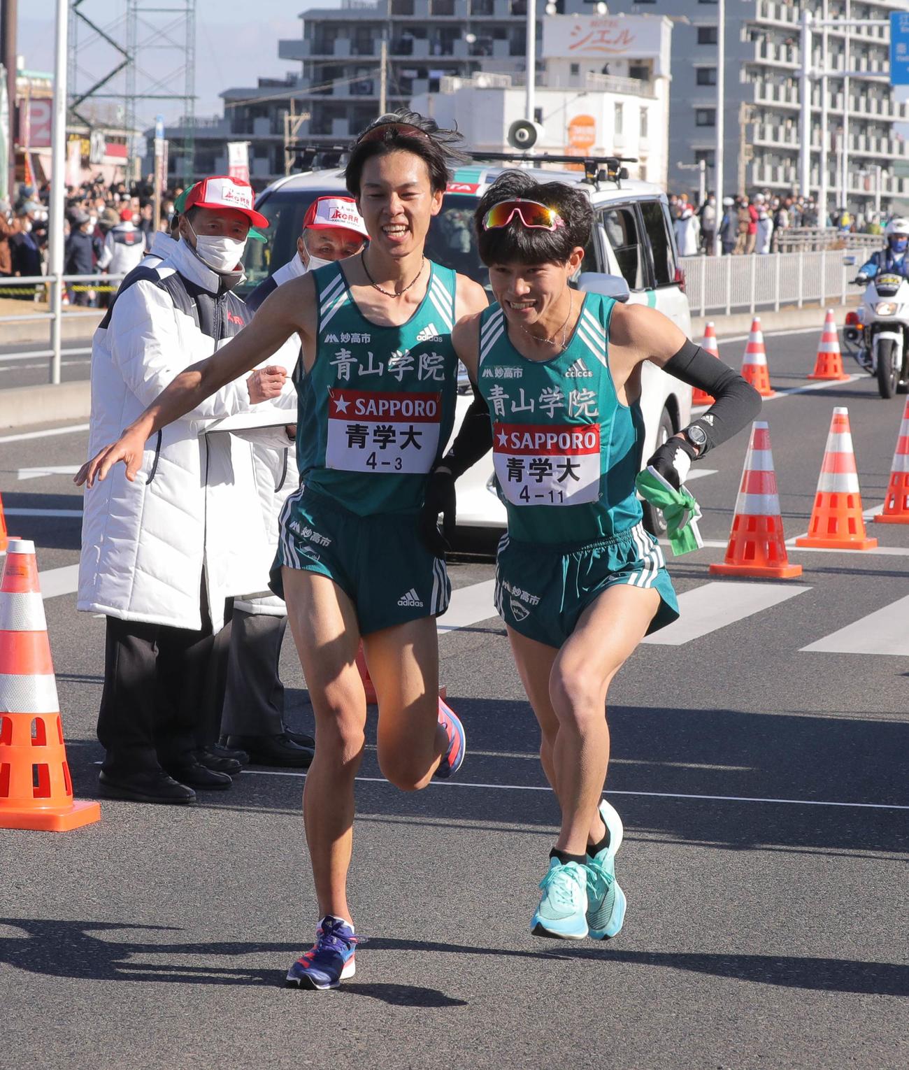 平塚中継所トップでタスキをつなぐ青学大3区の太田（左）と青学大4区の飯田（代表撮影）