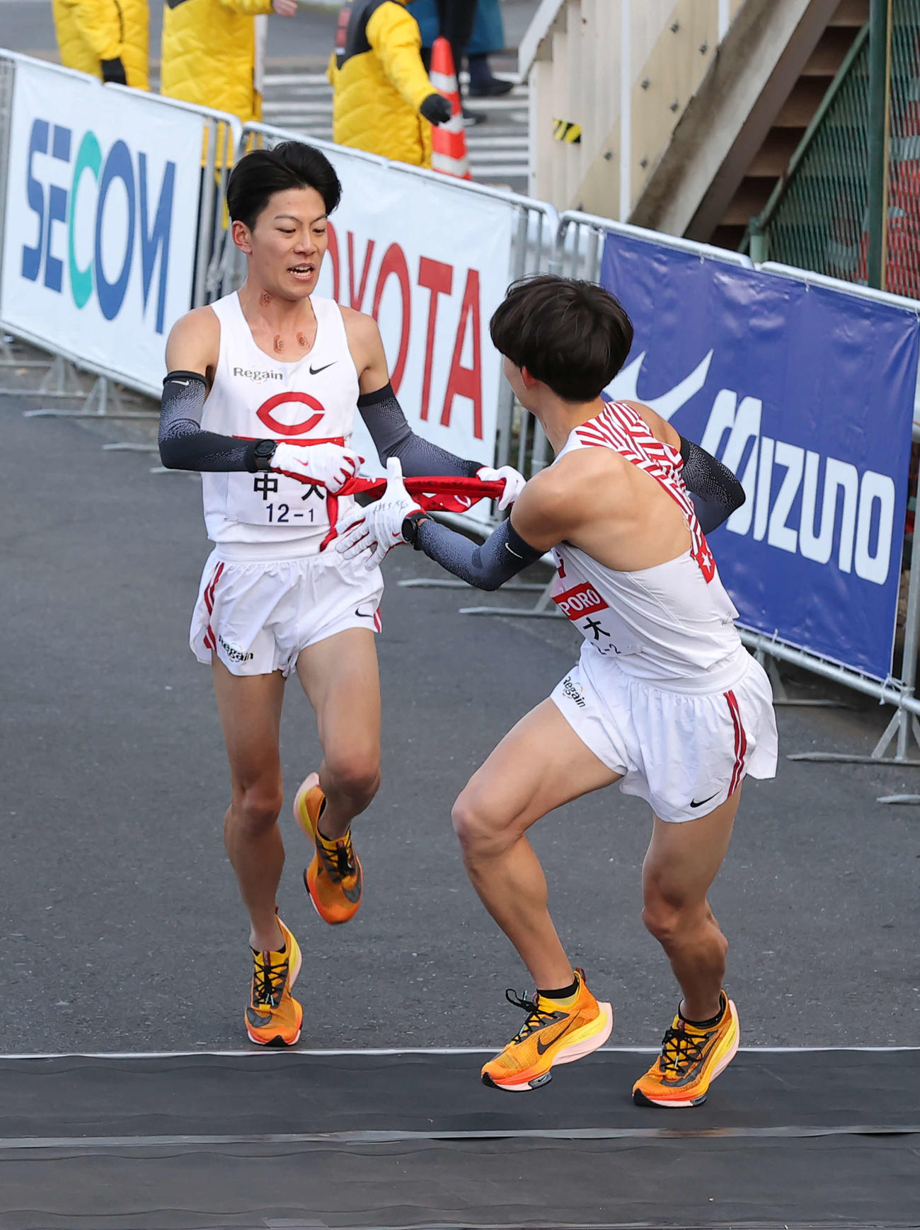 鶴見中継所、先頭でたすきをつなぐ中大1区吉居（左）と2区手島（撮影・河野匠）