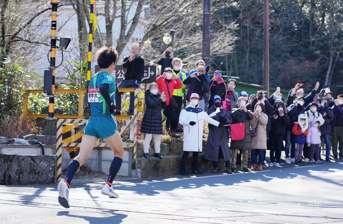 沿道の観客からの声援を受けながら箱根登山鉄道・小涌谷踏切を通過する青学大5区若林（撮影・菅敏）