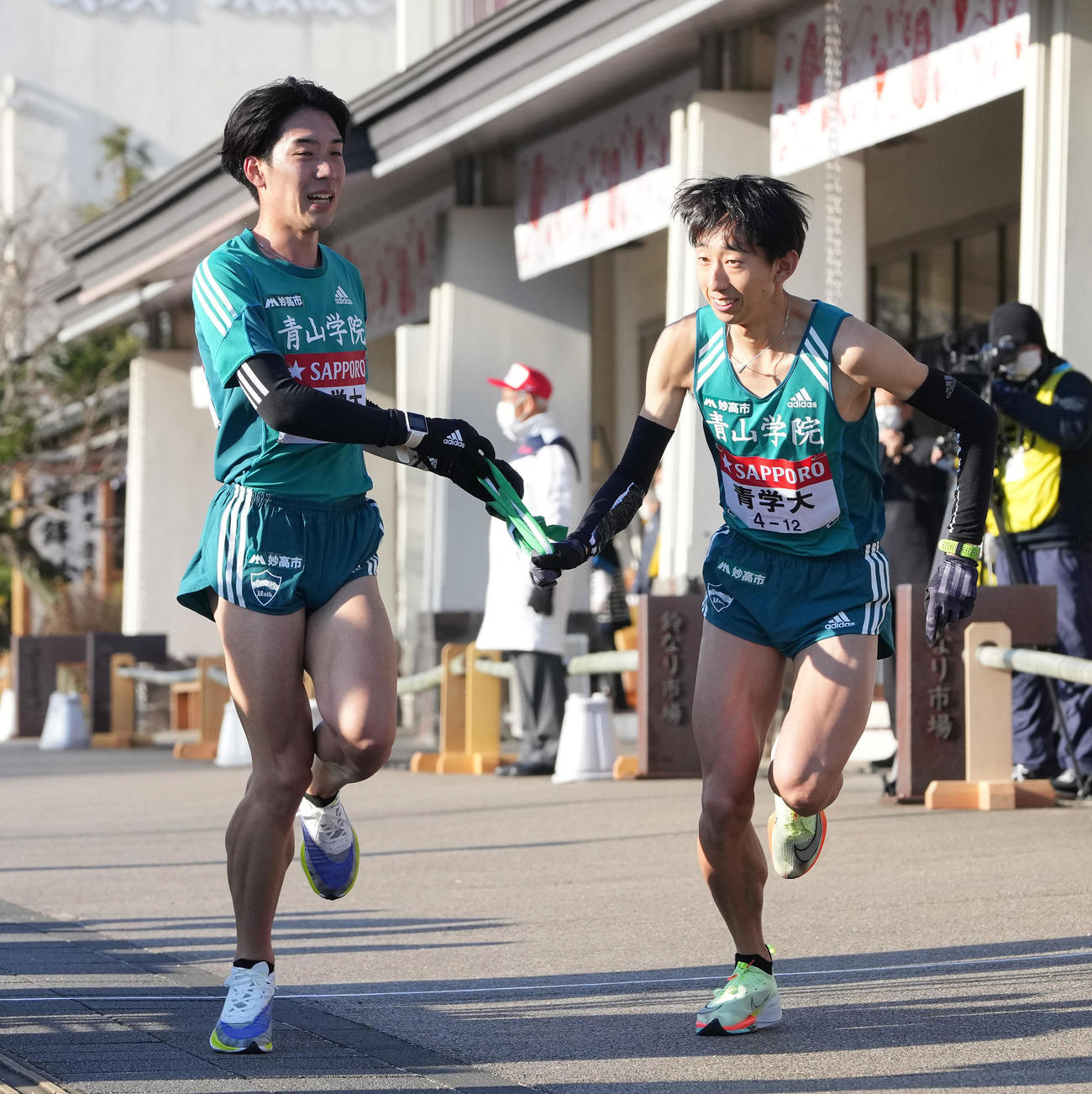 青学大6区高橋（左）は小田原中継所トップで7区岸本にたすきを渡す（撮影・鈴木みどり）