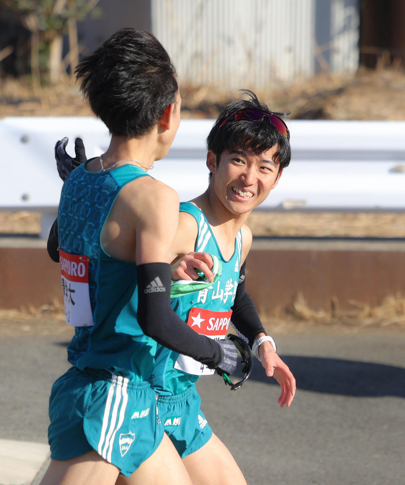 青学大7区岸本（左）と笑顔でタスキリレーする8区佐藤（撮影・河田真司）