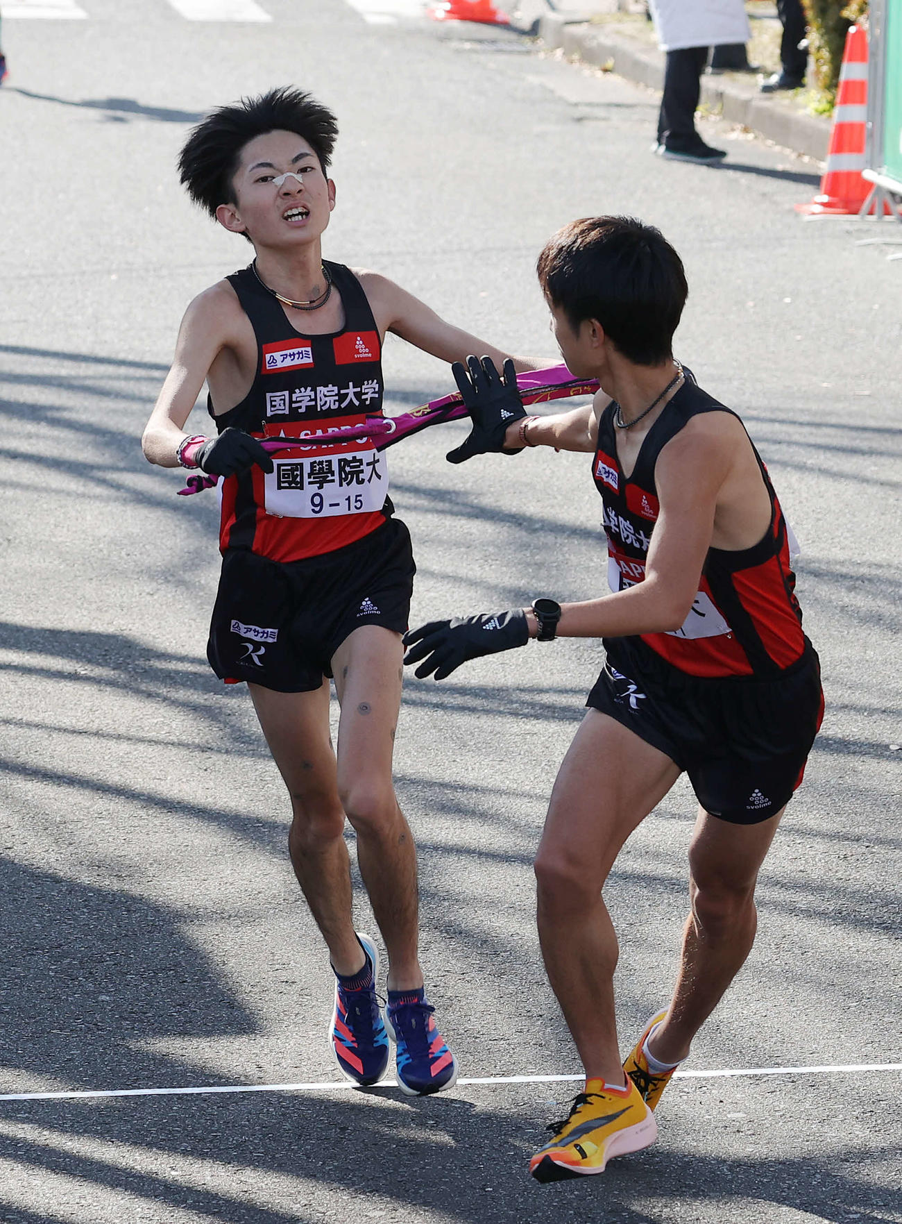 鶴見中継所、5位でたすきをつなぐ国学院大9区平林（左）と10区相沢（撮影・河野匠）