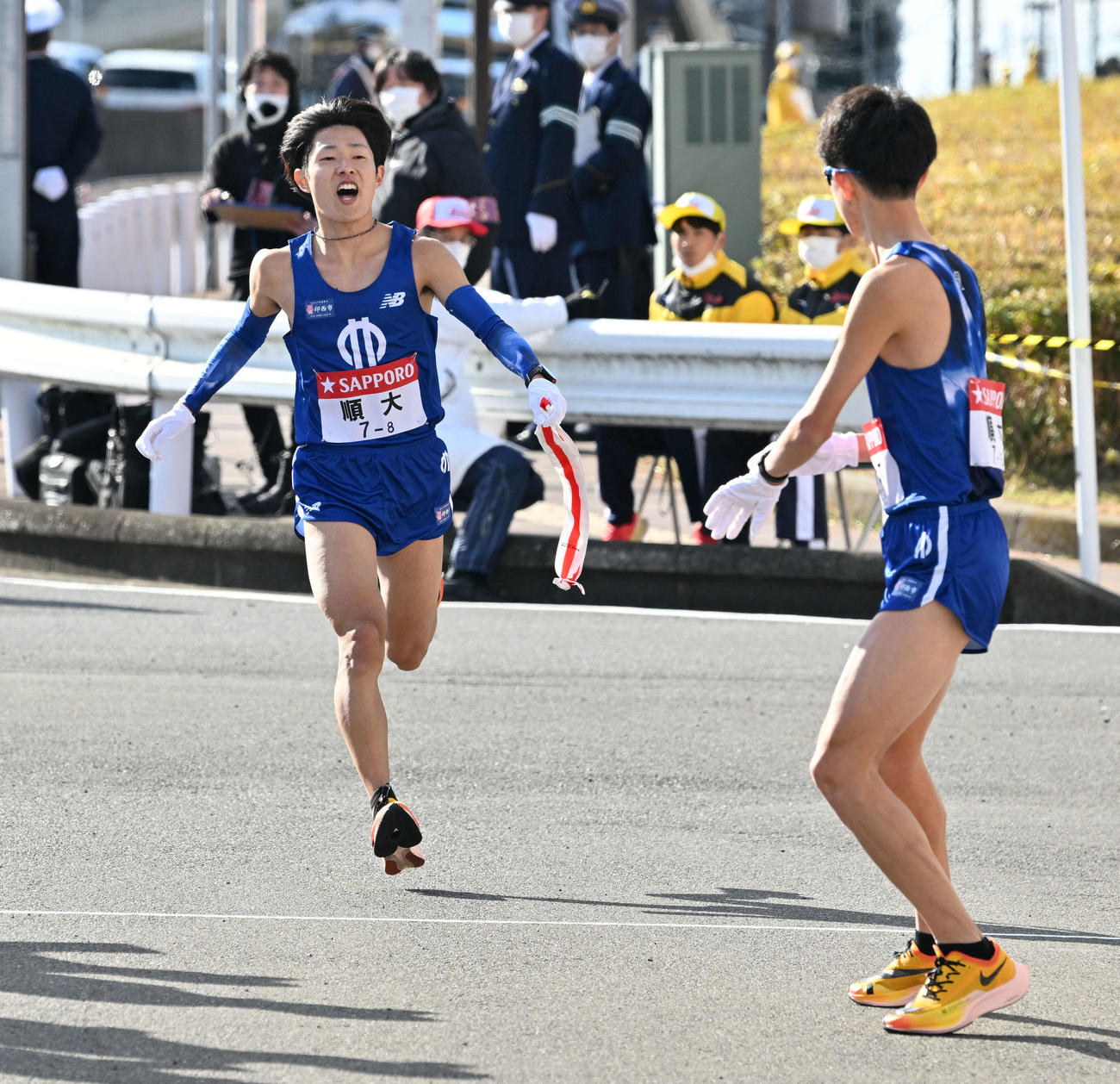 戸塚中継所で順大8区津田（左）は9区野村にたすきを渡す（撮影・滝沢徹郎）