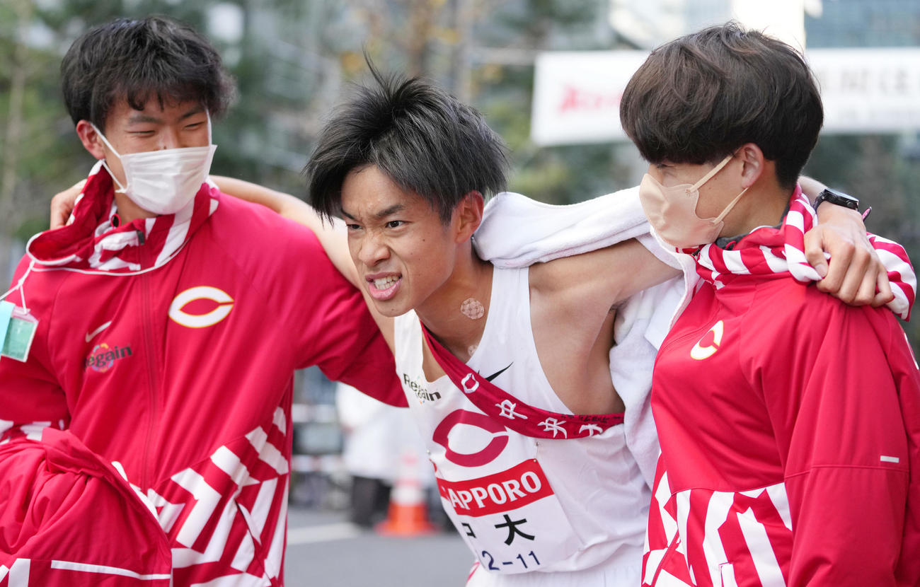 6位でゴールし、チームメイトに抱えられる中大10区井上（撮影・菅敏）