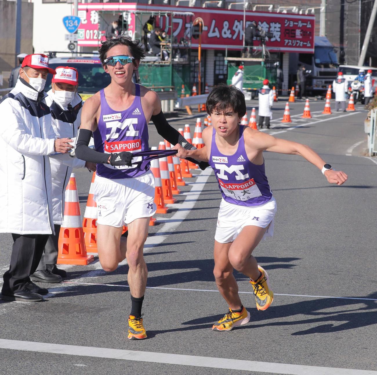 平塚中継所でタスキをつなぐ明大7区の富田（左）と8区の櫛田（代表撮影）