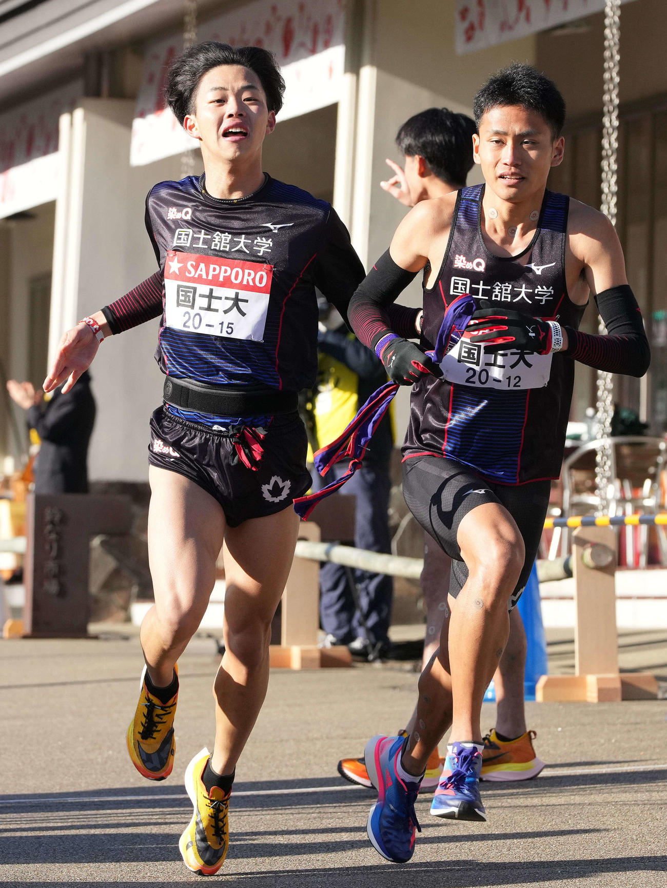 国士舘大6区福井（左）は小田原中継所で7区清水拓にたすきを渡す（撮影・鈴木みどり）