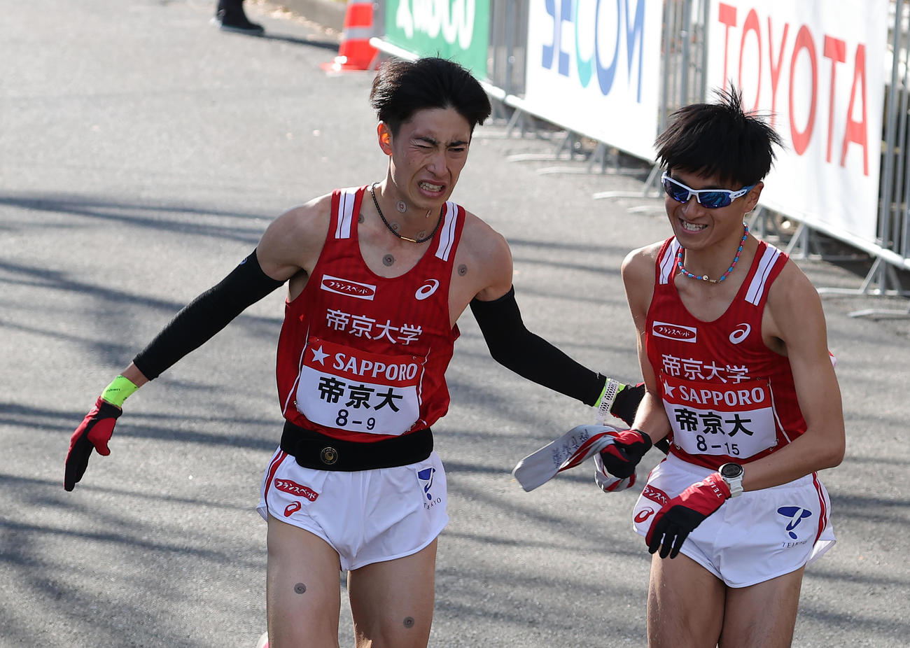 鶴見中継所、たすきをつなぐ帝京大9区森田（左）と10区西脇（撮影・河野匠）