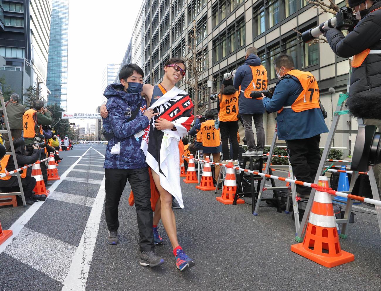 10位でゴールし、抱えられる法大アンカーの川上（中央右）（代表撮影）