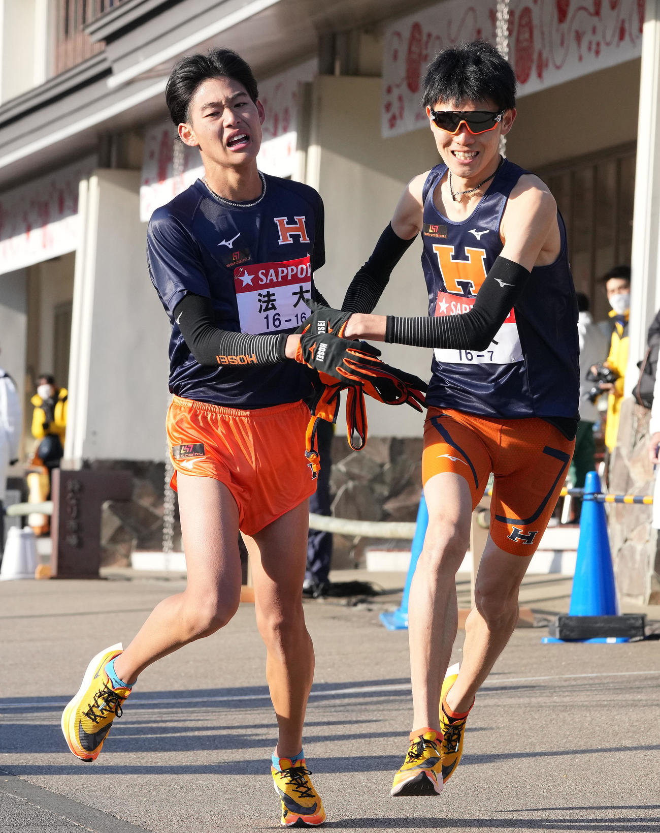 法大6区武田（左）は小田原中継所で7区中園にたすきを渡す（撮影・鈴木みどり）