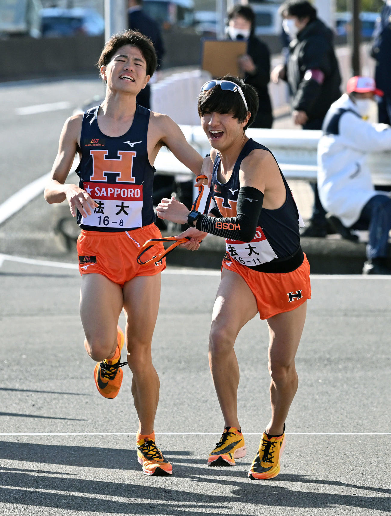 戸塚中継所で法大8区稲毛（左）は9区清家にたすきを渡す（撮影・滝沢徹郎）