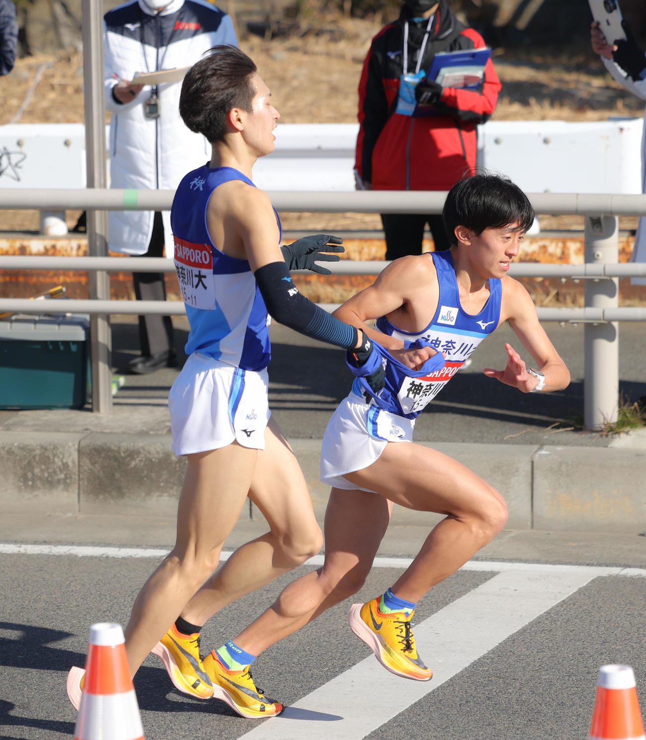 平塚中継所を13位でタスキリレーする神奈川大7区川口（左）と8区大泉（撮影・河田真司）