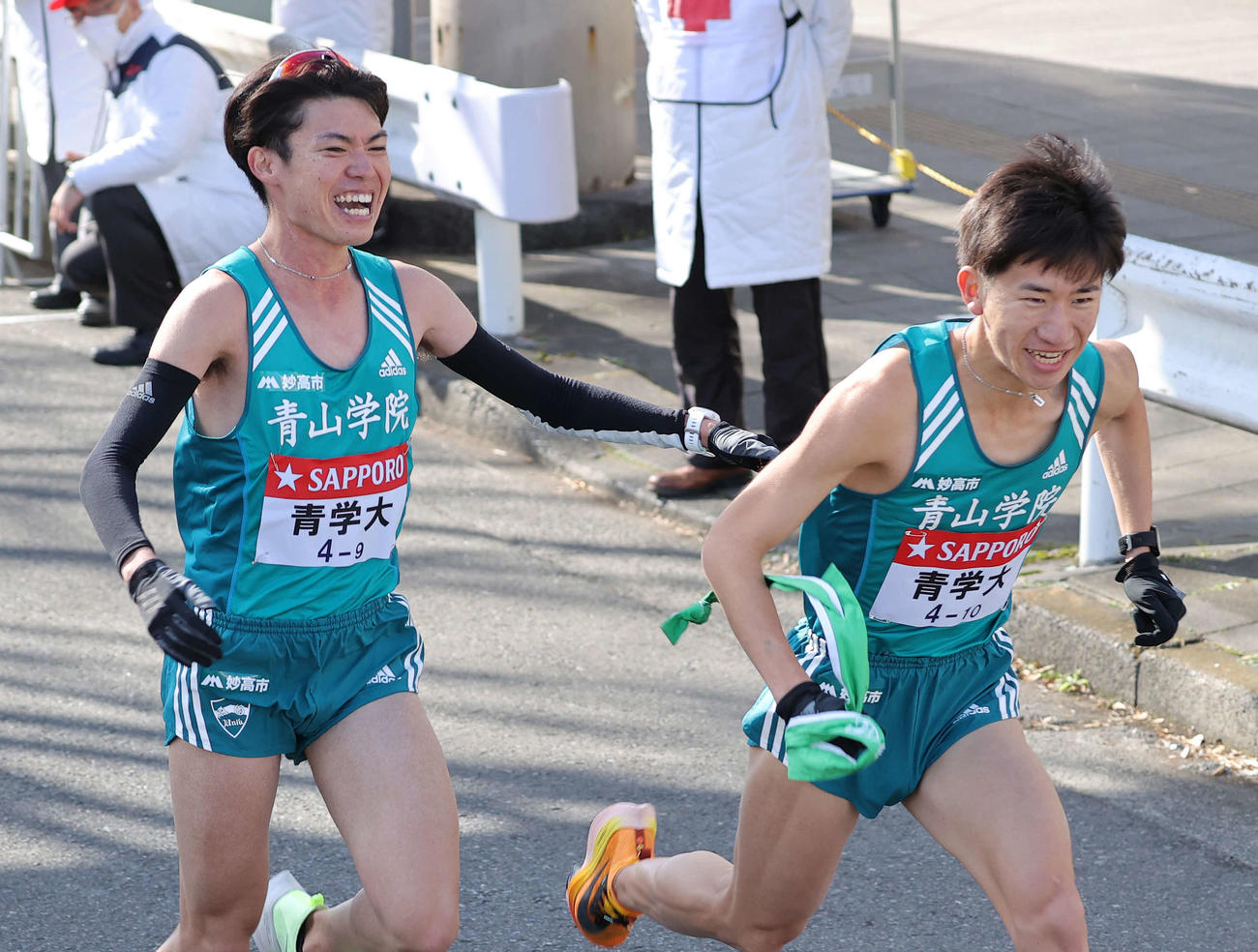 鶴見中継所、笑顔でたすきをつなぐ青学大9区中村（左）と10区中倉（撮影・河野匠）