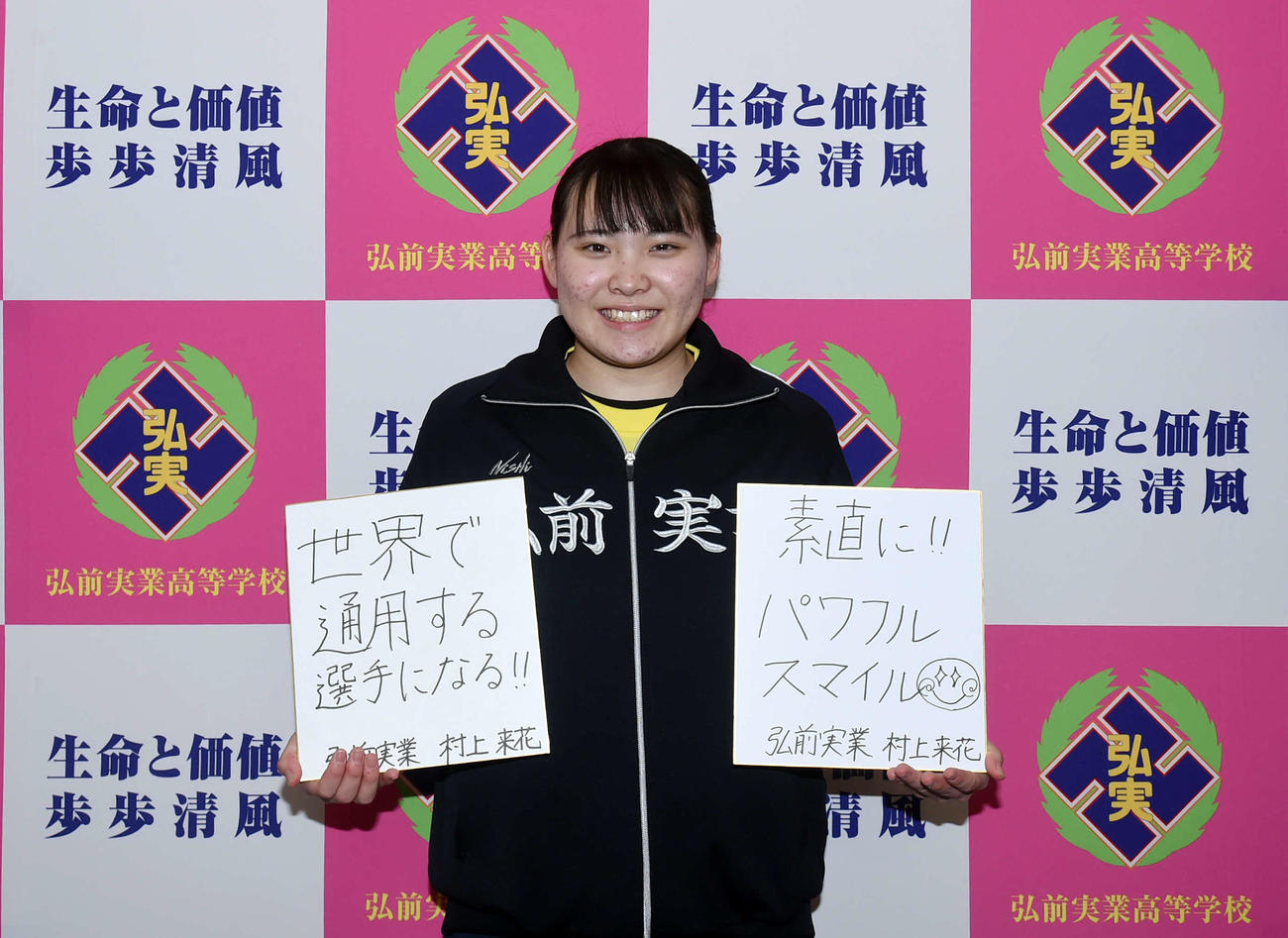 高校3年時の目標を書いた色紙（左）と卒業後の目標「素直に！！パワフルスマイル」と書いた色紙を持ち、笑顔を見せる弘前実・村上（撮影・相沢孔志）