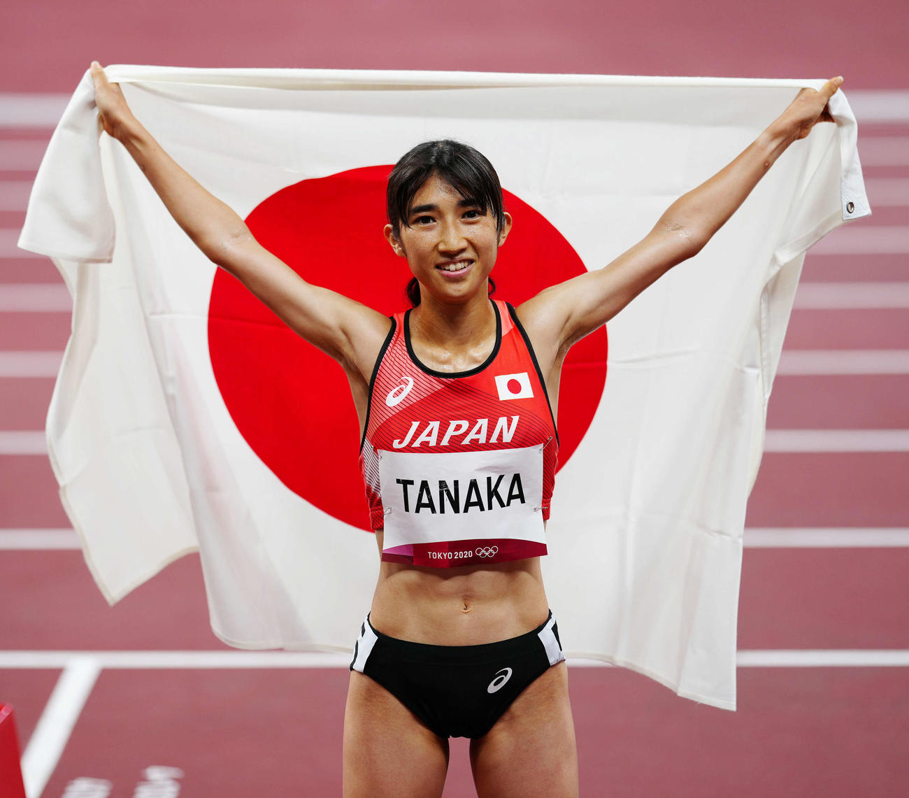 東京五輪の女子1500メートルで8位入賞し、日の丸を背に広げる田中希実（2021年8月6日撮影）