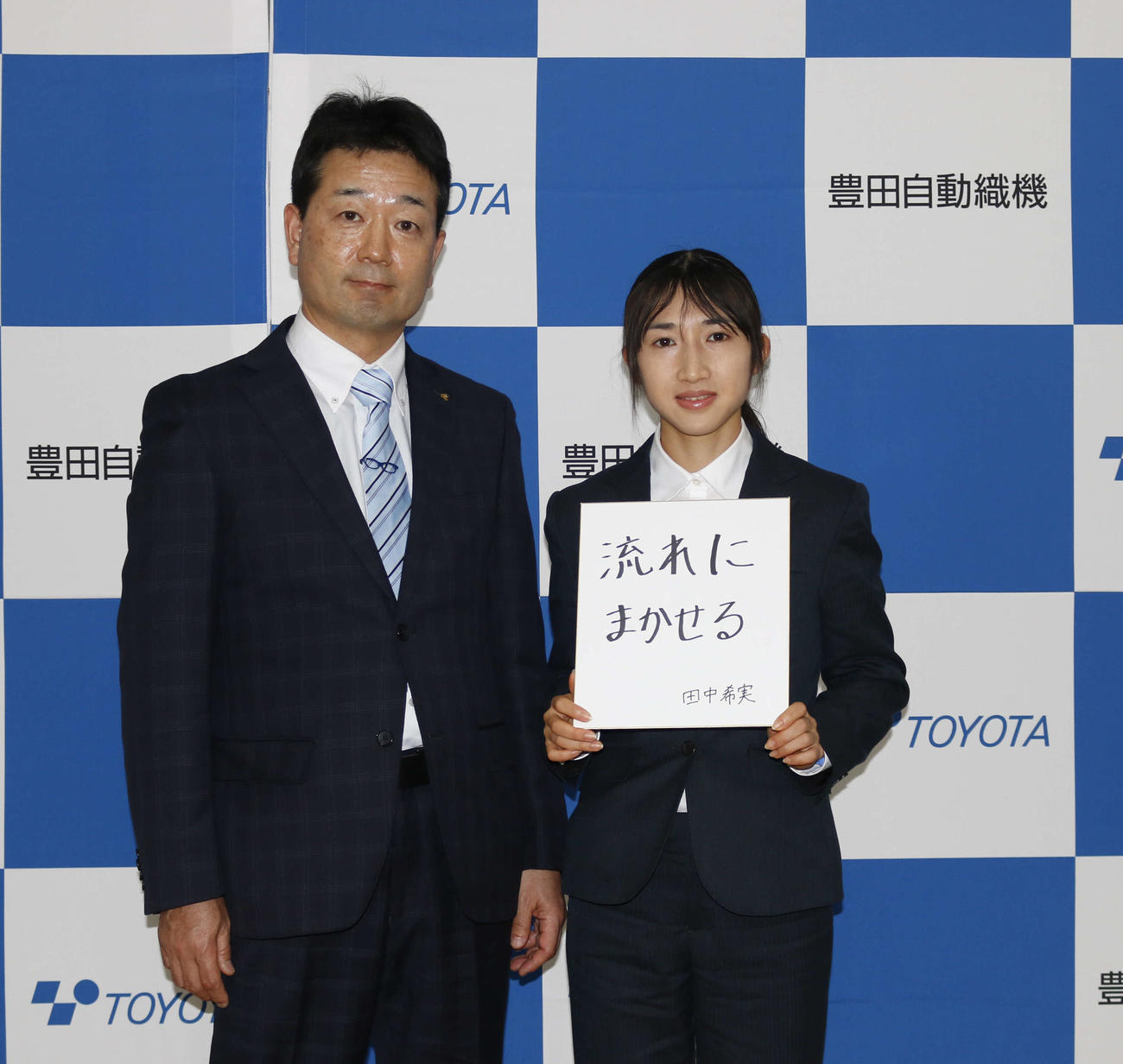 豊田自動織機の入社会見に臨み、新年度の意気込みを記した色紙を掲げる田中希実（右）と同社陸上競技部の幾世隆部長（撮影・佐藤礼征）