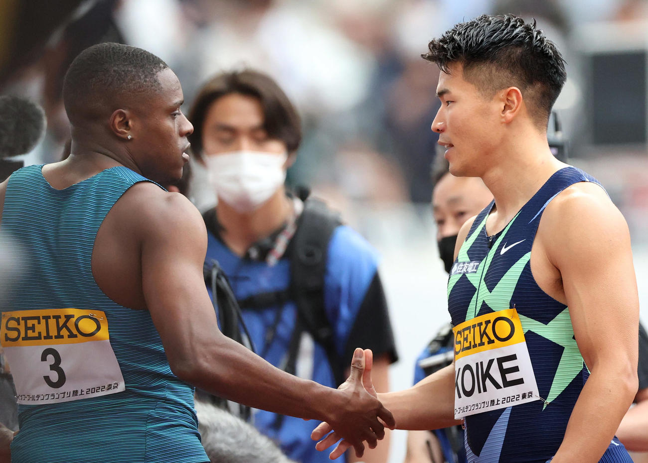 男子100メートルで優勝したコールマン（左）と握手をかわす2位の小池（撮影・狩俣裕三）