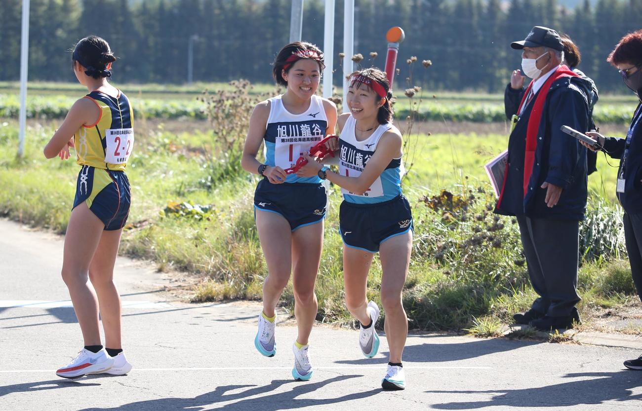 旭川龍谷の中野芽衣(中央左)、は2走の石川苺に笑顔でタスキを渡す(撮影・中島洋尚)　