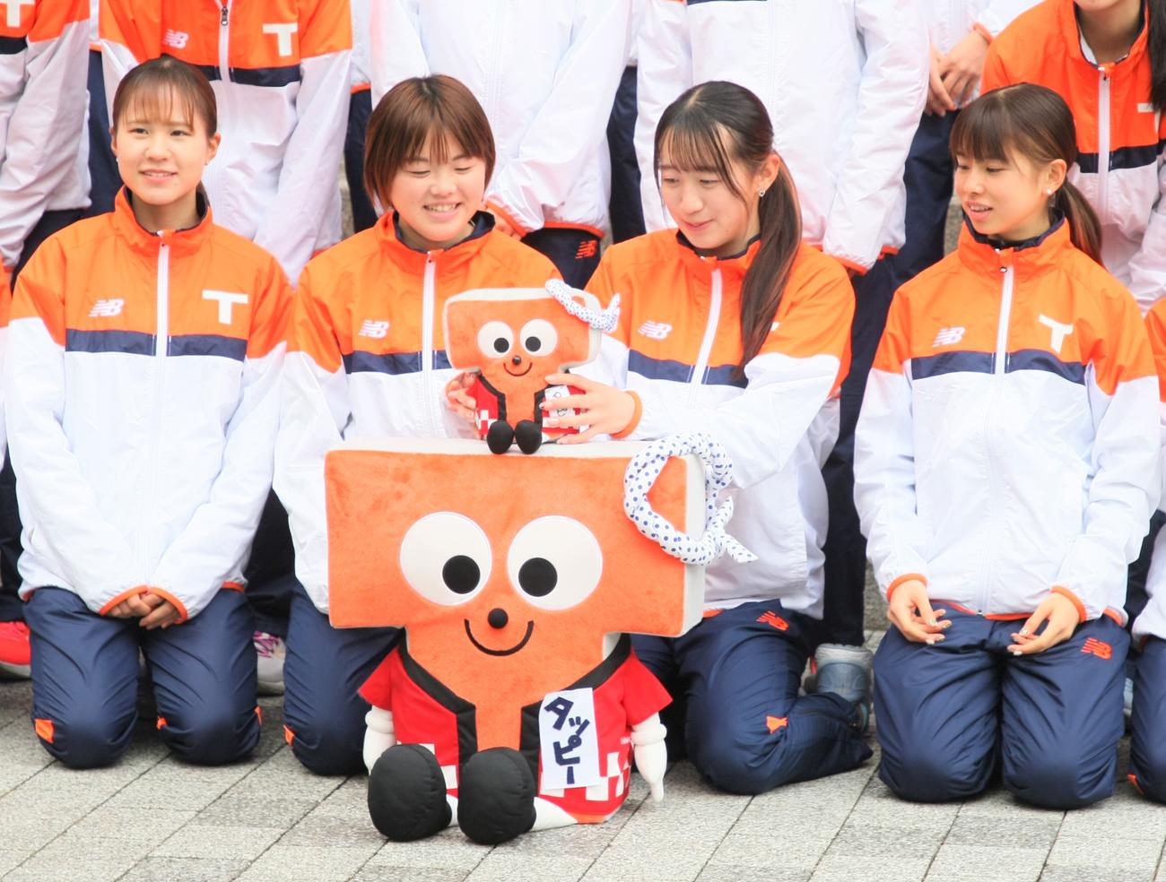 富士山女子駅伝の壮行会後の記念撮影で、拓大マスコットキャラクター「タッピー」の位置を調整する小沢主将（左から2人目）と牛（左から3人目）（撮影・藤塚大輔）
