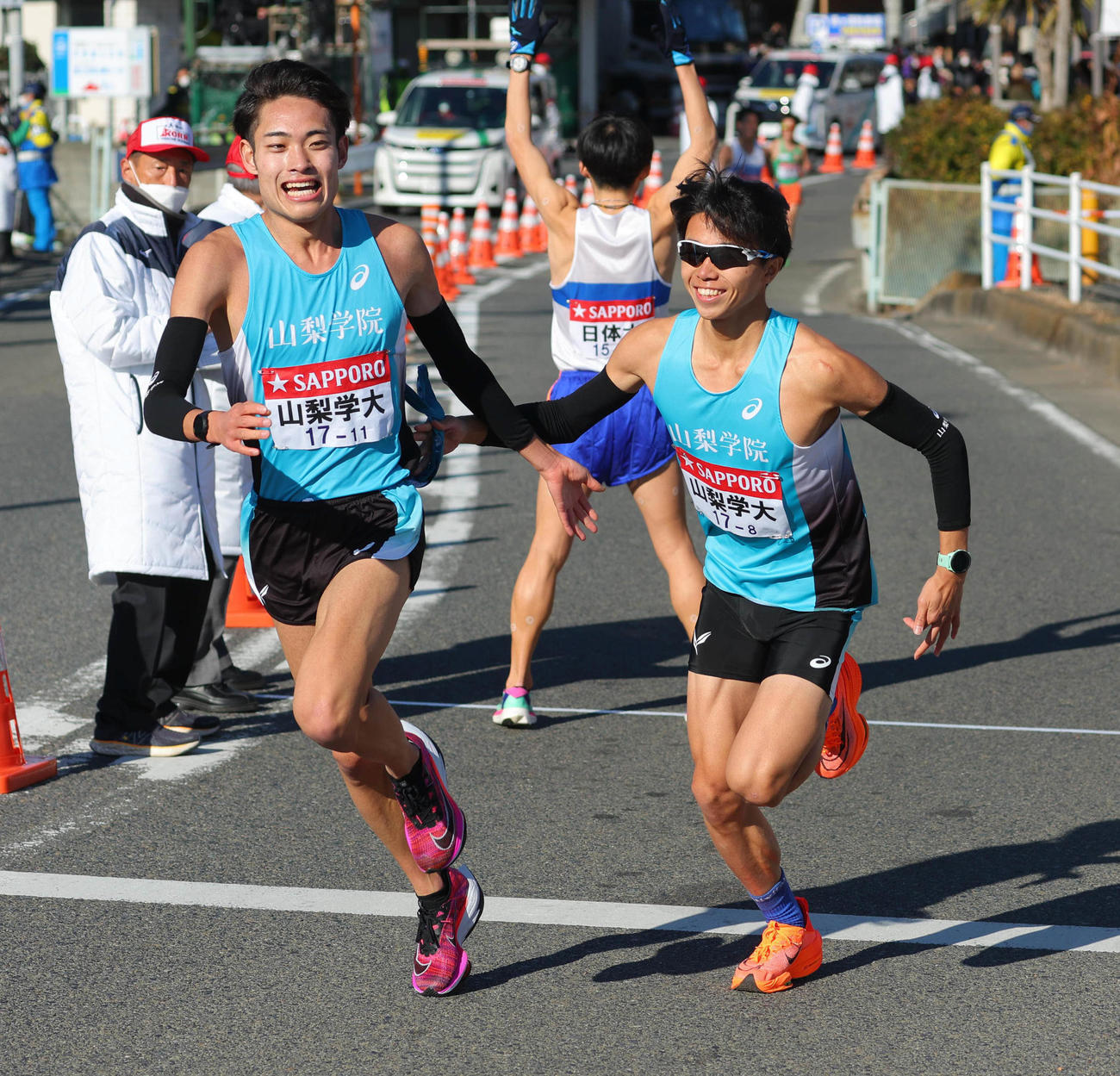 平塚中継所、14位でたすきをつなぐ山梨学院大7区石部（左）と8区伊東（代表撮影）