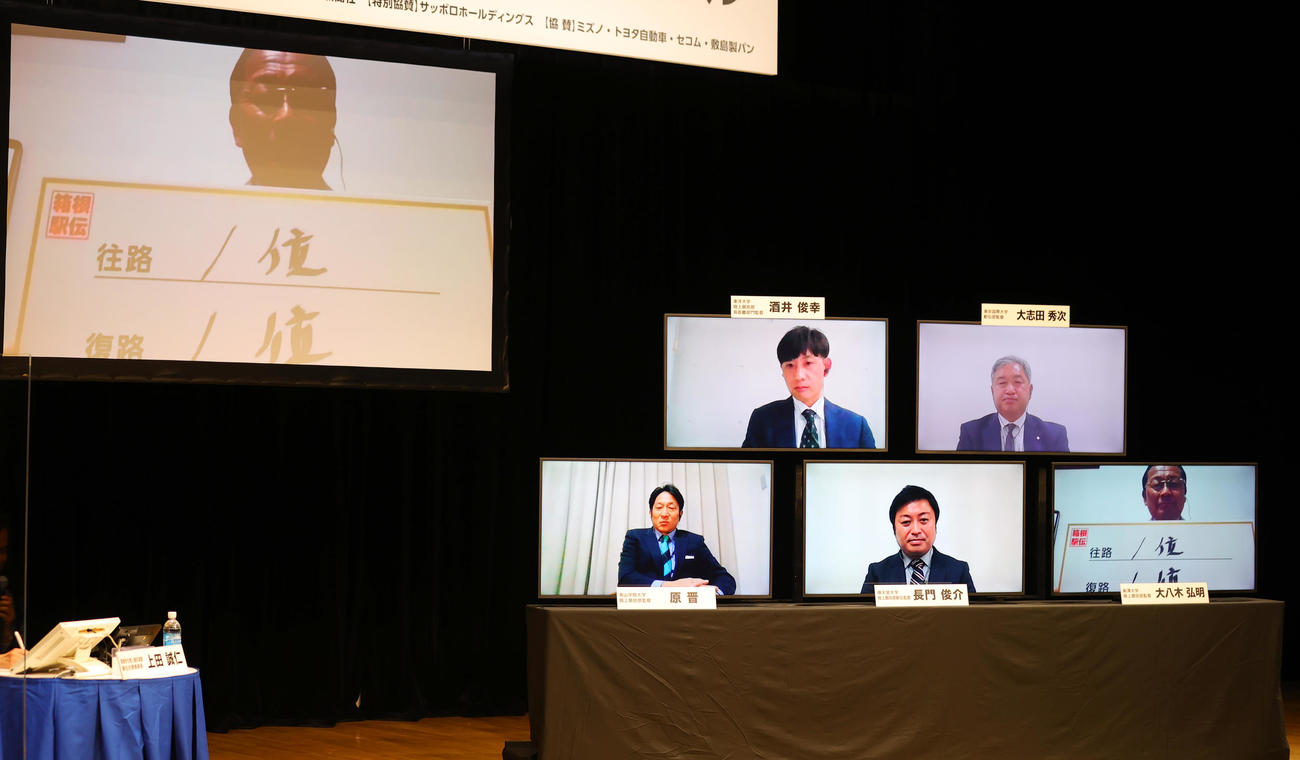 箱根駅伝監督トークバトルで、目標順位を記す駒大・大八木監督。右小モニター下段左から青学大・原監督、順大・長門監督、駒大・大八木監督、上段左から東洋大・酒井監督、東京国際大・大志田監督（撮影・野上伸悟）