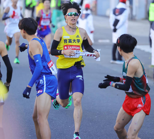 3位相当のタイムで2区麗沢大・工藤（右）にたすきをつなぐ1区関東学生連合の育英大・新田（撮影・野上伸悟）